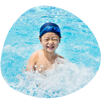smiling child in swimming pool, wearing swim cap and goggles