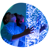 child is looking at up a blue lava/bubble sensory lamp